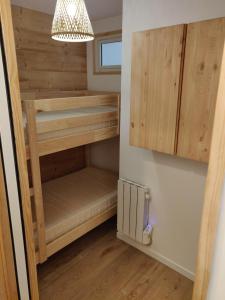 ein kleines Schlafzimmer mit Etagenbetten aus Holz in einem winzigen Haus in der Unterkunft Appartement neuf 4-6 pers. aux pieds des pistes in Génos