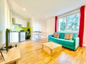 a living room with a blue couch and a kitchen at APPARTEMENTS "Pieds à Terre" à LORIENT - LUMINEUX - TOUT CONFORT in Lorient