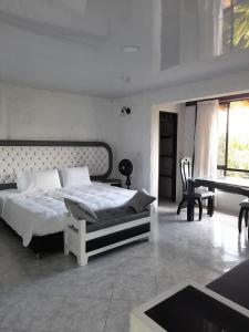 a white bedroom with a bed and a piano at Hotel Campestre Los Nogales in Quimbaya