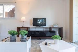 uma sala de estar com uma televisão de ecrã plano e duas mesas em Haus Berg 303 - Gramado (300 metros Rua Coberta) em Gramado