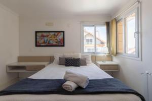 um quarto com uma grande cama branca e uma janela em Haus Berg 303 - Gramado (300 metros Rua Coberta) em Gramado