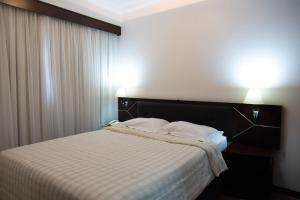 a bed in a hotel room with two lights on at The Palace Flat Moema particular in São Paulo