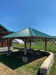 a picnic shelter with a green roof in a field at Vikendica Vlahović in Kolašin