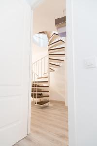 una scala a chiocciola in una camera bianca con pavimenti in legno di Spiral Stairs Duplex a Figueres