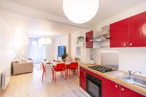 una cocina con armarios rojos y una mesa con sillas. en L'AMASSE Échappée Amboisienne T3 avec sauna partagé en Amboise