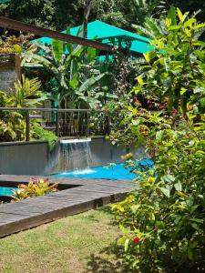 een waterval in een tuin met een houten loopbrug bij Paraíso Azul Retiro in Praia de Freguesia de Santana