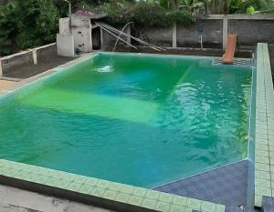 a large swimming pool with green water at RedDoorz Plus At Grand Yustik Sukabumi in Sukabumi