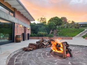a fire pit in front of a building with logs at Fijnbosch Game Lodge Jeffreys Bay in Jeffreys Bay