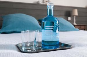 - une bouteille et un verre sur un plateau sur un lit dans l'établissement La Ferme d'Ervee de Saint-Roch, à Isigny-sur-Mer