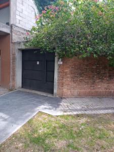 un garaje con una puerta negra y una pared de ladrillo en Jardin Secreto en Rosario