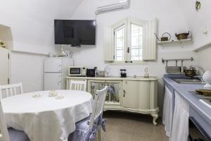 eine Küche mit einem Tisch und einem TV an der Wand in der Unterkunft Andrew'S home - Luisanna in Torre Pali 