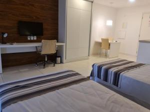 a hotel room with two beds and a desk and a tv at Flat Particular - SHN - Vista Livre Esplanada in Brasilia