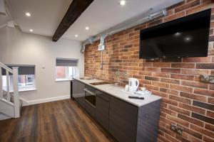 a kitchen with a brick wall and a flat screen tv at Three Cranes Serviced Apartments in Sheffield
