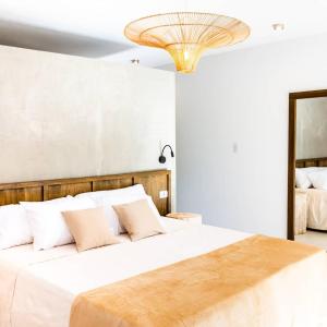 a bedroom with a bed with white sheets and a chandelier at Favre Suites in Mina Clavero