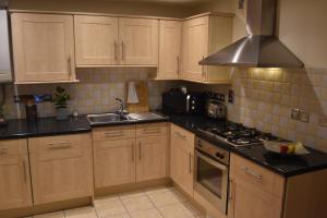 a kitchen with wooden cabinets and a stove top oven at Scandinavian City Centre Apartment in Worcester