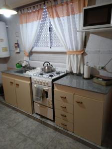 cocina con fogones, fregadero y ventana en Depto Av Pringles en Olavarría
