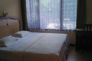 a bedroom with a bed and a large window at Hotel Olibert Parapat Ajibata Mitra RedDoorz in Parapat