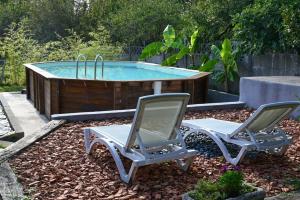 two chairs and a swimming pool in a yard at La Maison d'à coté in Naucelle