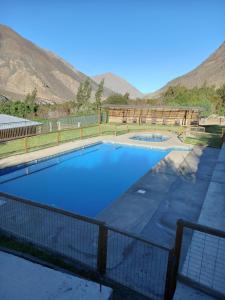 a swimming pool with a fence and mountains in the background at Cabañas Rivadavia Spa in Vicuña