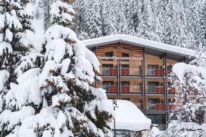 un edificio con alberi innevati di fronte ad esso di Design Oberosler Hotel a Madonna di Campiglio