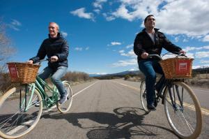 two men riding bikes down a road with baskets at My Pod House in Esquel