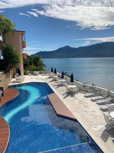 a resort swimming pool with chairs and the water at Pontal das Marinas Frente Ilhabela in São Sebastião
