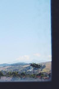 una ventana con vistas a una ciudad con palmeras en Paradise Hostel e Flats, en Itatiaia