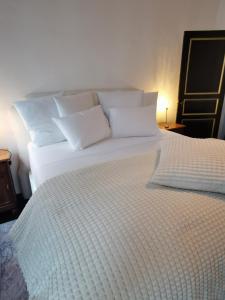 a large white bed with white pillows on it at Chantilly Townhouse in Ghent
