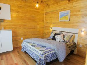 a bedroom with a bed and wooden walls at Quinta dos Ventos Chalé in Urubici