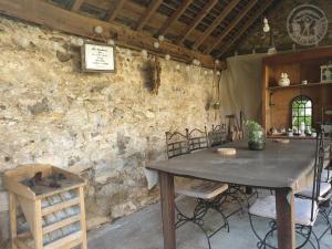 a table and chairs in a room with a stone wall at Gite charm'en Vexin in Neuilly-en-Vexin