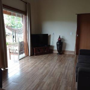 a living room with a wooden floor and a flat screen tv at Casa Kali - O seu refúgio nas montanhas! in Sao Jorge