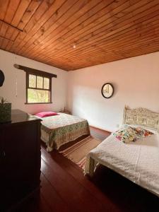 - une chambre avec 2 lits et une horloge murale dans l'établissement Casa em Ibitipoca - 7 pessoas, à Lima Duarte