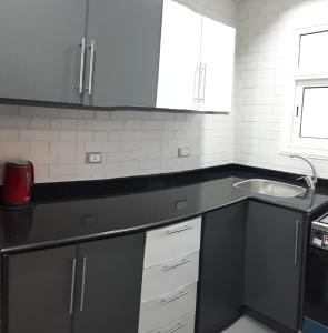Una cocina con encimera negra y fregadero. en Madinaty 2, en Madīnat ash Shurūq 2 fotos más