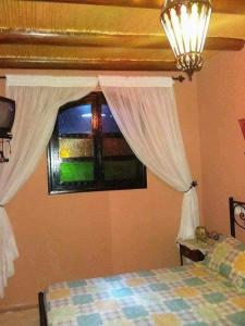 Taourirtにあるberber houseのベッドとカーテンのついた窓のある寝室