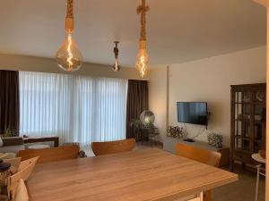 een woonkamer met een grote houten tafel en verlichting bij Northastic Suite in Oostende