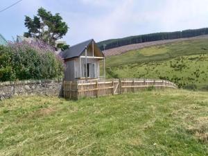 a wooden cabin in a field with a fence at North Muasdale Farm in Muasdale