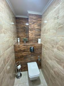 a bathroom with a toilet and wooden walls at DendrariumParkApartments in Chişinău