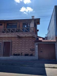 a brick house with a balcony and a garage at Studio Baleia Franca in Imbituba