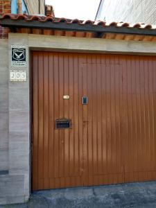 une porte de garage marron avec un panneau sur celle-ci dans l'établissement Gara Hospedaria 2, à Imbituba