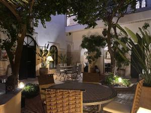 un patio con mesa, sillas y árboles en Riad Amegrad en Marrakech