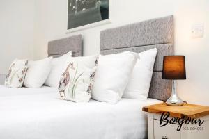 a bed with white pillows and a lamp on a table at Bright New Town 2BR-1BA, 1 min to George St - Free Parking by Bonjour Residences Edinburgh in Edinburgh