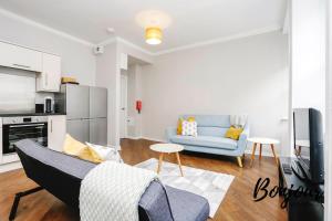 a living room with a blue couch and a kitchen at Bright New Town 2BR-1BA, 1 min to George St - Free Parking by Bonjour Residences Edinburgh in Edinburgh