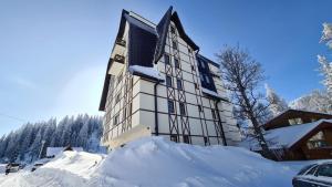 a building covered in snow with a pile of snow at Nivalis Residence A11 in Jahorina