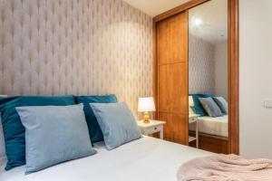 a bedroom with a bed with blue pillows and a mirror at Fabuloso apartamento - Prado Museum in Madrid