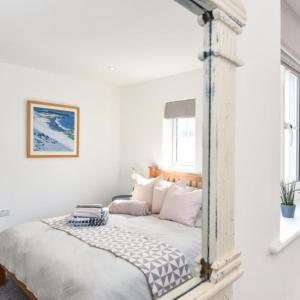 a bedroom with white walls and a bed with a mirror at The Little House, boutique home near the sea in Chichester
