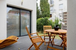 eine Terrasse mit Tisch und Stühlen auf einem Deck in der Unterkunft La Villetta G Riedisheim - appartement de Standing in Riedisheim