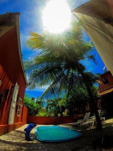 un palmier et une piscine bleue en face d'un bâtiment dans l'établissement Casa Vermelha Búzios, à Búzios