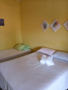 sypialnia z białym łóżkiem z obrazami na ścianie w obiekcie Recanto Saqua w mieście Saquarema