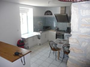 een keuken met een tafel en stoelen en een keuken met witte kasten bij 14 maison 6 pers Les Gîtes Bigoudens in Plonéour-Lanvern