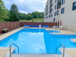 a swimming pool with chairs and a building at Ski-In Ski-out Luxury Condo with Hot Tub and pools in Snowshoe